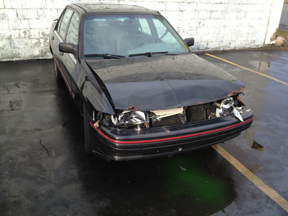 Black sedan with damaged front end and grille