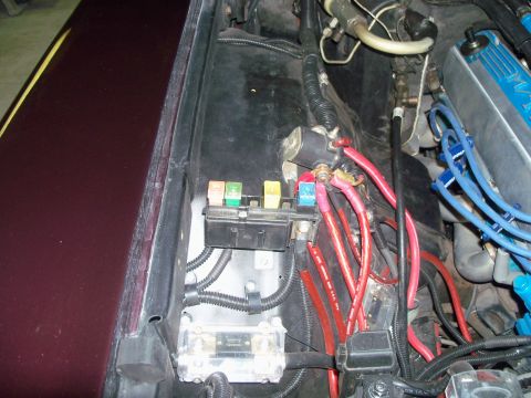 1979 Ford Ranchero - Under-hood wiring detail on the driver's inner fender of a burgundy car, showing a blade fuse block with colored ATO fuses, a mounted solen…