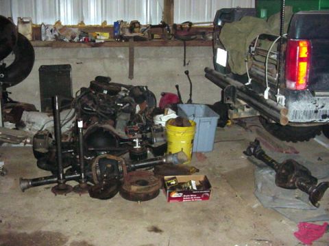1992 Ford Bronco - Various vehicle parts are laid out on the floor of a garage, with the rear of a truck visible.