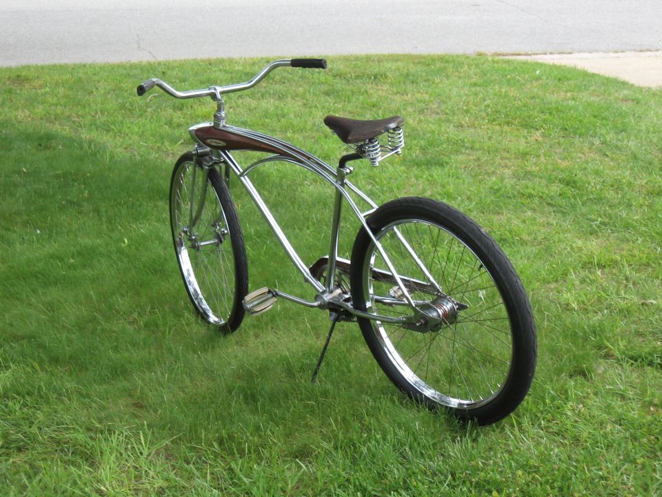 Chrome cruiser bicycle with brown seat and wood-grain accents on the frame, parked on grass