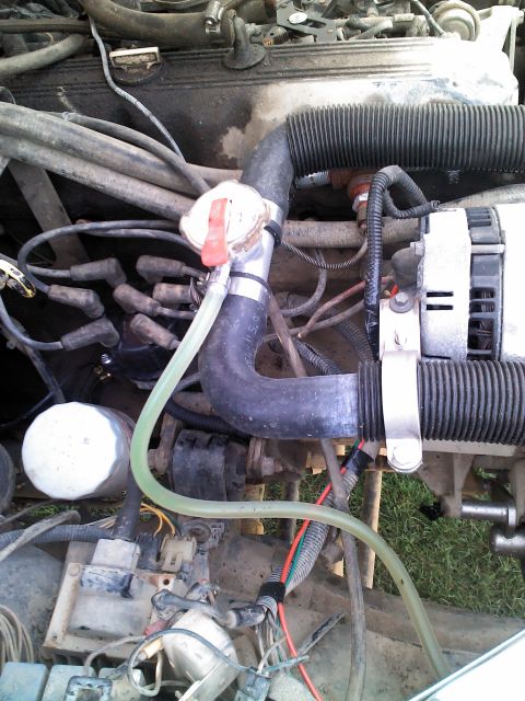 1987 Jeep Comanche - The engine bay of a 1987 Jeep Comanche shows various components including hoses, wires, and the alternator.