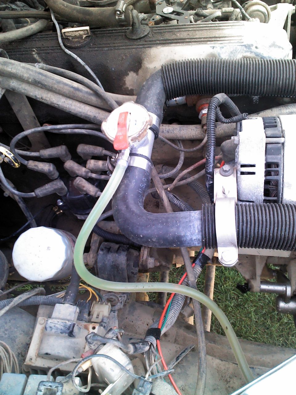 1987 Jeep Comanche engine bay with hoses, wires, and alternator