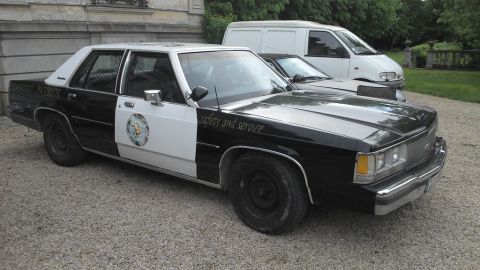 1991 Ford LTD Crown Victoria - This 1991 Ford Crown Victoria police car is parked next to a white van.