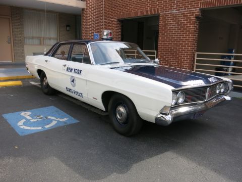 1991 Ford LTD Crown Victoria - front of a white-and-black classic Ford New York State Police sedan with dome light, parked in a handicap space.
