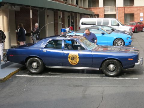 1991 Ford LTD Crown Victoria - dark blue classic Plymouth sedan with a Trumbull Police door seal parks at a motel as a man stands beside it.