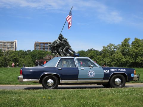 1991 Ford LTD Crown Victoria - two-tone blue 90E STATE POLICE sedan in side profile is parked on grass before the Iwo Jima Marine Corps Memorial.