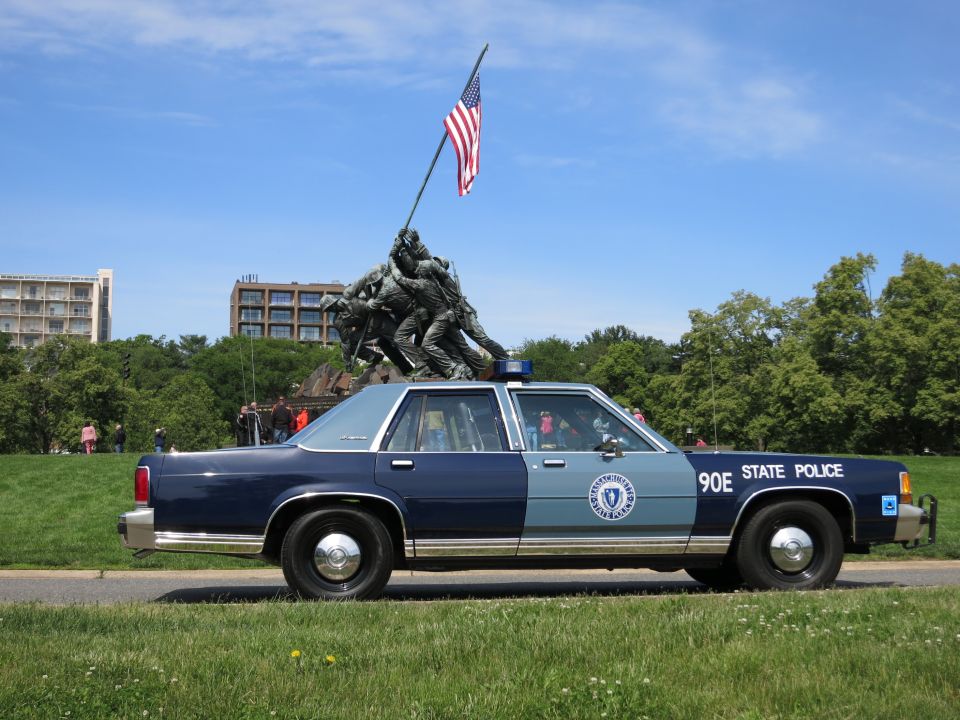 Blue STATE POLICE sedan 90E in profile before the Iwo Jima Memorial