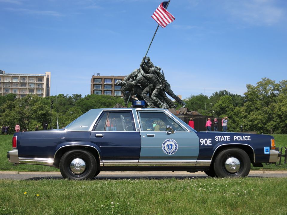 Blue STATE POLICE sedan 90E in profile before the Iwo Jima Memorial