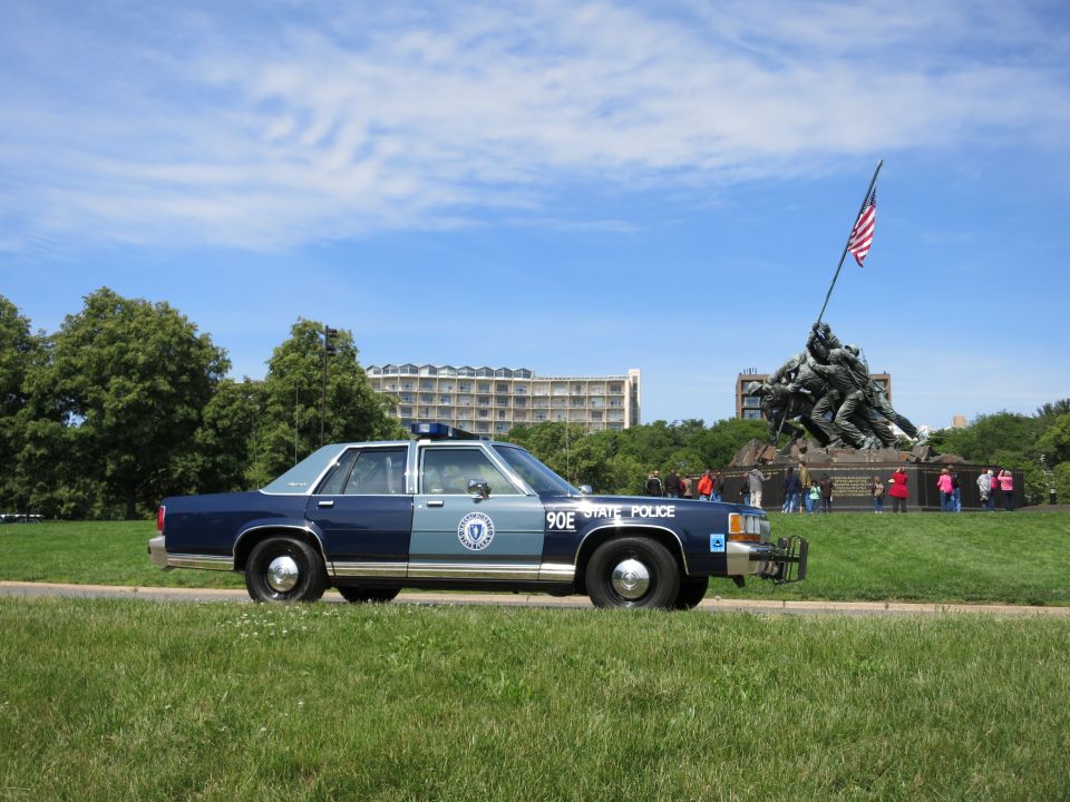 Close rear-quarter view of a blue STATE POLICE sedan 90E before the Iwo Jima Memorial
