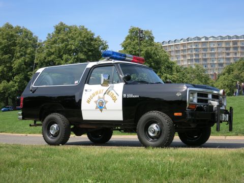 1991 Ford LTD Crown Victoria - Front-quarter view of a black-and-white Dodge Ram Charger Highway Patrol SUV with a front push bar parked on a paved path.