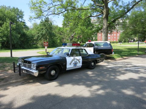1991 Ford LTD Crown Victoria - black-and-white Highway Patrol sedan parked on a tree-shaded road with a matching patrol SUV behind it.