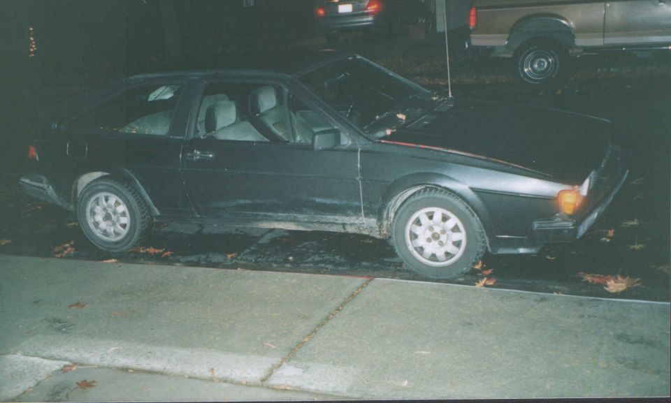 Dark VW Scirocco coupe in side view parked at night with hood open