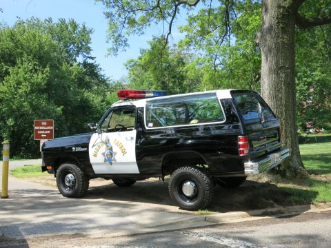 1991 Ford LTD Crown Victoria - black-and-white Dodge Ramcharger SUV lettered California Highway Patrol sits parked near trees with its roof light bar.