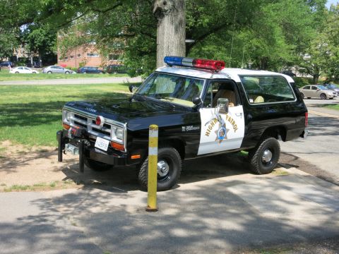 1991 Ford LTD Crown Victoria - black-and-white Dodge Highway Patrol SUV fitted with a front winch and roof light bar is parked on grass.