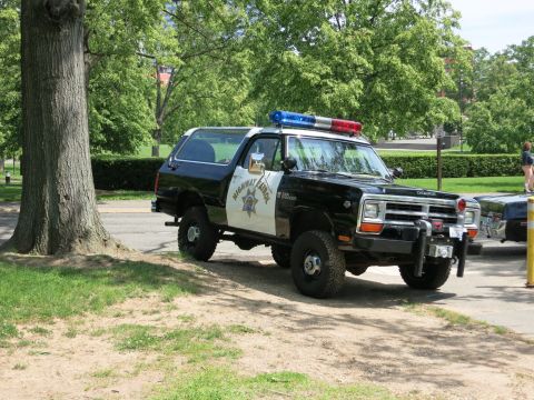 1991 Ford LTD Crown Victoria - black-and-white Dodge Highway Patrol SUV with a front winch and roof lights is parked beside a large tree.