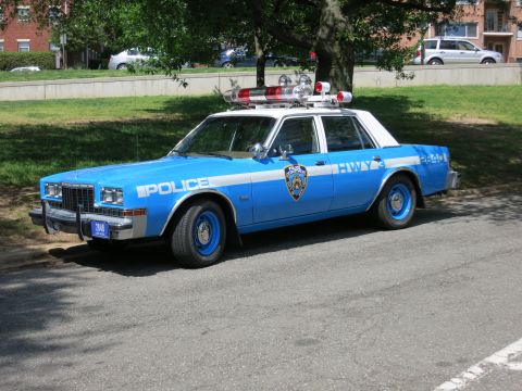 1991 Ford LTD Crown Victoria - blue-and-white NYPD Highway police sedan with a full roof light bar and blue wheels is parked along a curb.