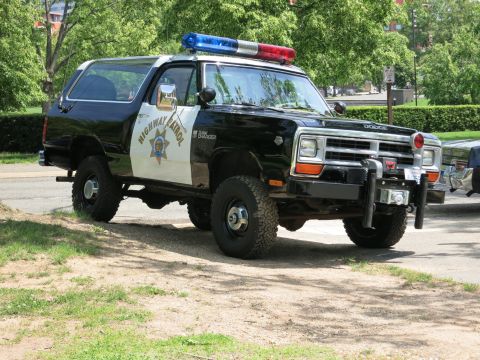 1991 Ford LTD Crown Victoria - black-and-white Dodge Ramcharger SUV lettered 'HIGHWAY PATROL' with a star emblem and roof light bar parked beside a road.