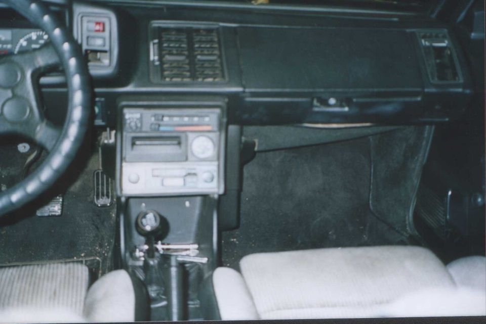 Car interior with dashboard, radio, manual shifter and gray seats