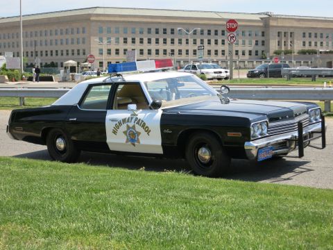 1991 Ford LTD Crown Victoria - black-and-white California Highway Patrol-style sedan with a roof lightbar sits on grass before the Pentagon building.