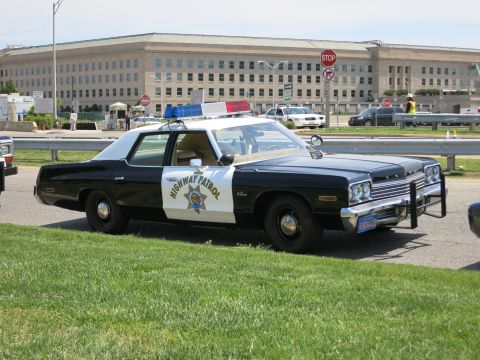 1991 Ford LTD Crown Victoria - vintage black-and-white Highway Patrol sedan with a gold star door emblem and roof lights is parked outside the Pentagon.