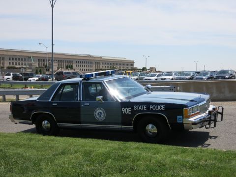 1991 Ford LTD Crown Victoria - two-tone blue State Police cruiser marked 90E with a state seal door decal is parked near the Pentagon.