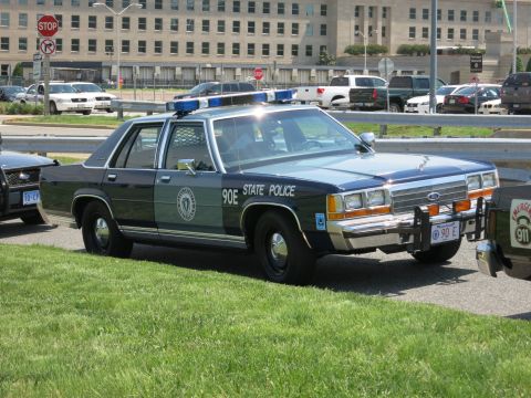 1991 Ford LTD Crown Victoria - two-tone Ford State Police sedan marked 90E with roof lightbar and push bumper sits on grass before the Pentagon.