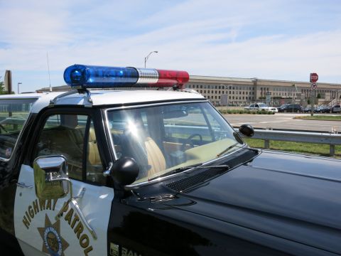 1991 Ford LTD Crown Victoria - Close-up of a Highway Patrol cruiser's red and blue roof lightbar and windshield with the Pentagon in the background.