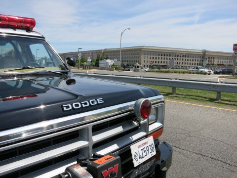 1991 Ford LTD Crown Victoria - Close-up of a black Dodge police pickup grille with a red beacon and California plate, parked near the Pentagon.