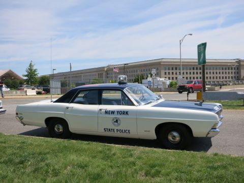 1991 Ford LTD Crown Victoria - vintage white-and-blue New York State Police four-door sedan parked on grass in front of the Pentagon.