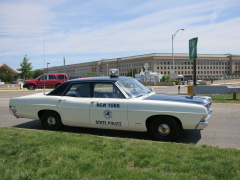 1991 Ford LTD Crown Victoria - Side profile of a classic New York State Police sedan with roof antenna and spotlight parked by the Pentagon.