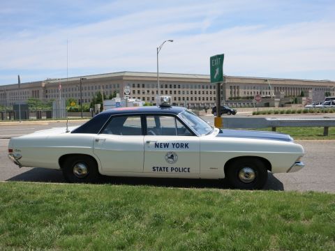 1991 Ford LTD Crown Victoria - Profile view of a vintage New York State Police sedan parked on a curb with the Pentagon in the background.