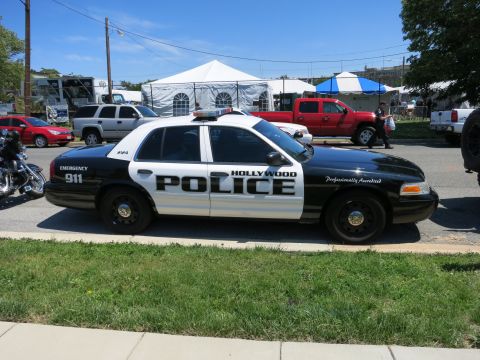 1991 Ford LTD Crown Victoria - black-and-white Hollywood Police Ford Crown Victoria patrol car marked EMERGENCY 911 parked along a grassy curb.