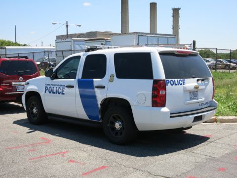 1991 Ford LTD Crown Victoria - Rear three-quarter view of a white Federal Protective Service Police Chevrolet Tahoe SUV parked near an industrial building.