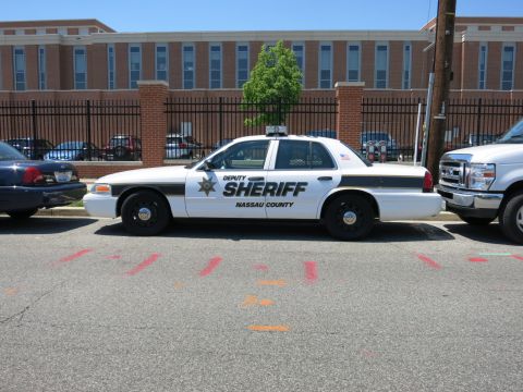1991 Ford LTD Crown Victoria - white Nassau County Deputy Sheriff Ford Crown Victoria patrol car parked along a street by a brick building.