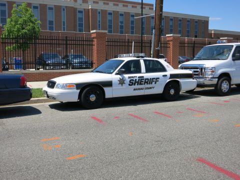1991 Ford LTD Crown Victoria - white Nassau County Deputy Sheriff Ford Crown Victoria patrol car parked at a curb beside a white van.