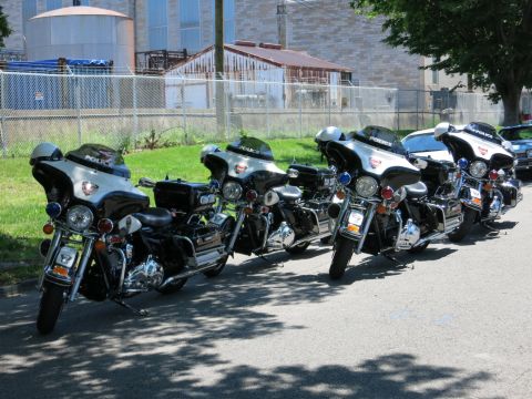 1991 Ford LTD Crown Victoria - line of black-and-silver police touring motorcycles parked in a row on pavement beside a chain-link fence.