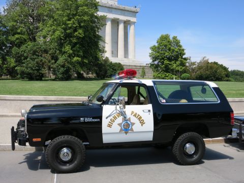 1991 Ford LTD Crown Victoria - black-and-white Dodge Ramcharger marked HIGHWAY PATROL parked in front of a columned memorial building.