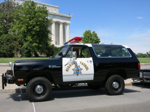 1991 Ford LTD Crown Victoria - black-and-white Dodge Ramcharger Highway Patrol SUV with a winch and roof light parked before a stone memorial.