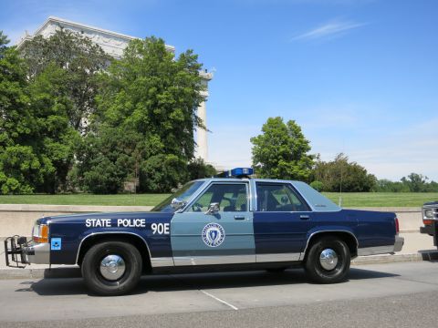1991 Ford LTD Crown Victoria - Side view of a blue-and-silver Massachusetts State Police Ford Crown Victoria marked STATE POLICE 90E with a push bar.