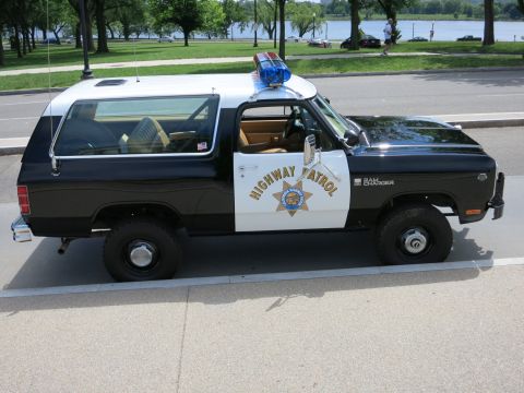 1991 Ford LTD Crown Victoria - black-and-white Highway Patrol SUV badged Ram Charger sits in profile along a waterfront roadway.