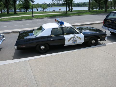 1991 Ford LTD Crown Victoria - black-and-white Highway Patrol sedan sits curbside ahead of a matching marked station wagon by the water.