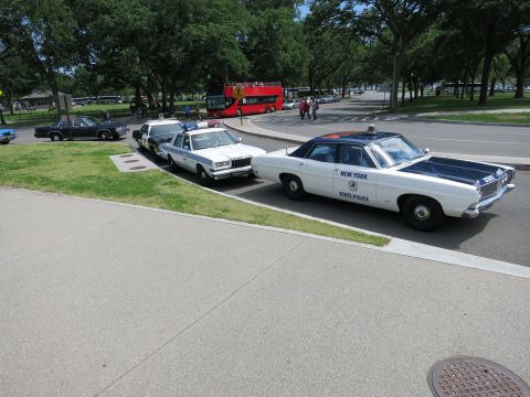 1991 Ford LTD Crown Victoria - white 'New York State Police' sedan with chrome grille is parked front three-quarter beside other police cars.