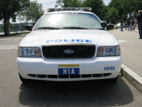 1991 Ford LTD Crown Victoria - Head-on front view of a white Ford police car marked POLICE, with H1A front plate, unit 115150, and a Ford grille emblem.