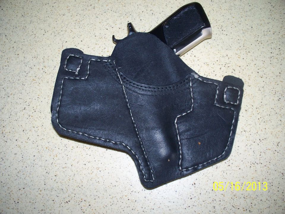 Black leather IWB holster with white stitching holding a compact stainless-slide pistol