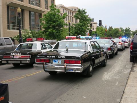 1991 Ford LTD Crown Victoria - black-and-white Chevrolet Caprice marked Highway Patrol sits among other police cruisers on a downtown street with emergency lights flashin…