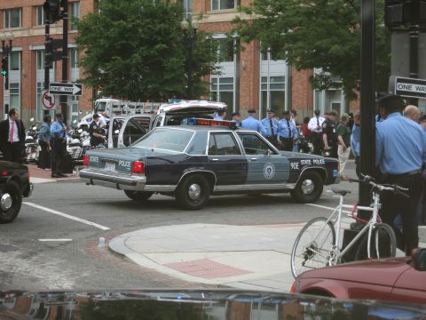 1991 Ford LTD Crown Victoria - dark blue Massachusetts State Police Ford Crown Victoria with light bar sits at a downtown intersection as uniformed officers stand nearby.