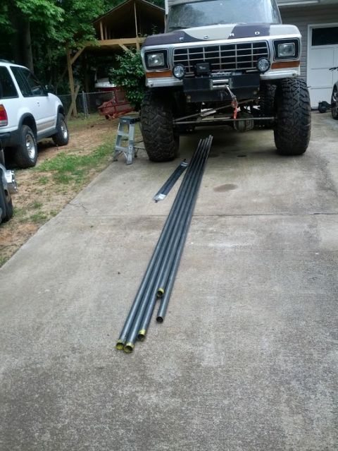 1979 Ford F-150 - A lifted 1979 Ford F-150 is parked on a driveway with metal pipes laid out in front of it.