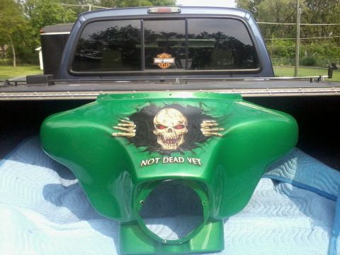 2003 Ford Crown Victoria - A custom green motorcycle fairing a skull graphic with skeletal hands bursting through and the text 'NOT DEAD YET' is shown in the bed of a…