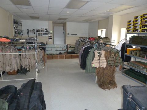 1992 Ford Mustang - Store interior displaying a variety of military-style clothing and tactical gear on racks and shelves.