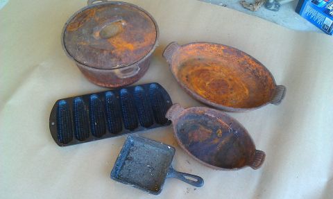1989 Ford Bronco - A collection of heavily rusted cast iron cookware, including a lidded pot and various pans, is arranged on a textured surface.
